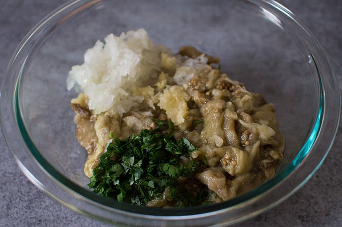 A bowl of roasted mashed eggplant, minced onion, garlic, and parsley.