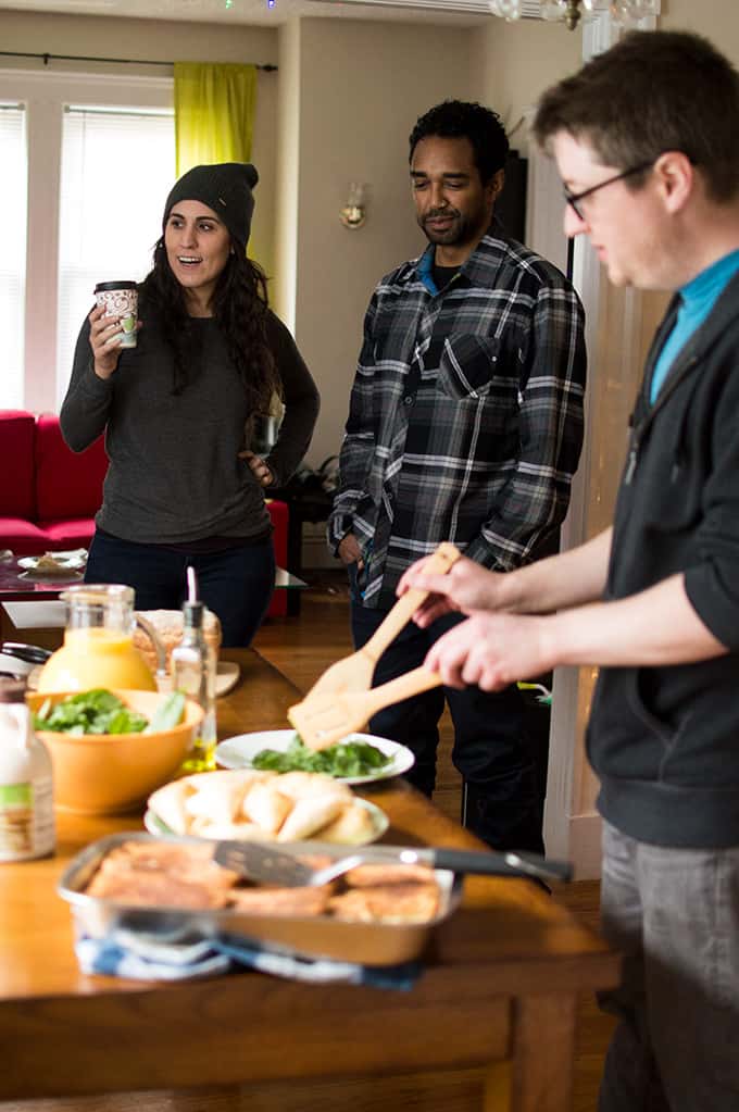 A group of people standing around a table with food.