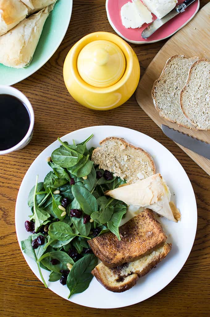 A plate of baked French toast, salad, and toast on a table with a cup of coffee.