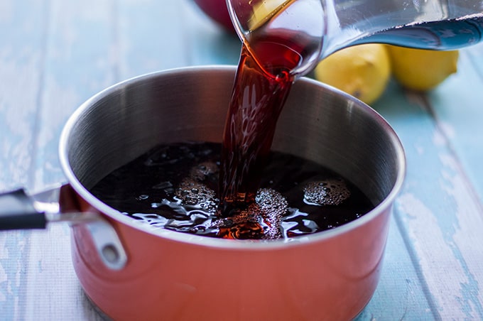 Pomegranate juice being poured into a saucepan.