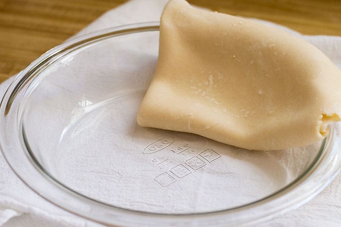 Pie dough folded over a pie dish.