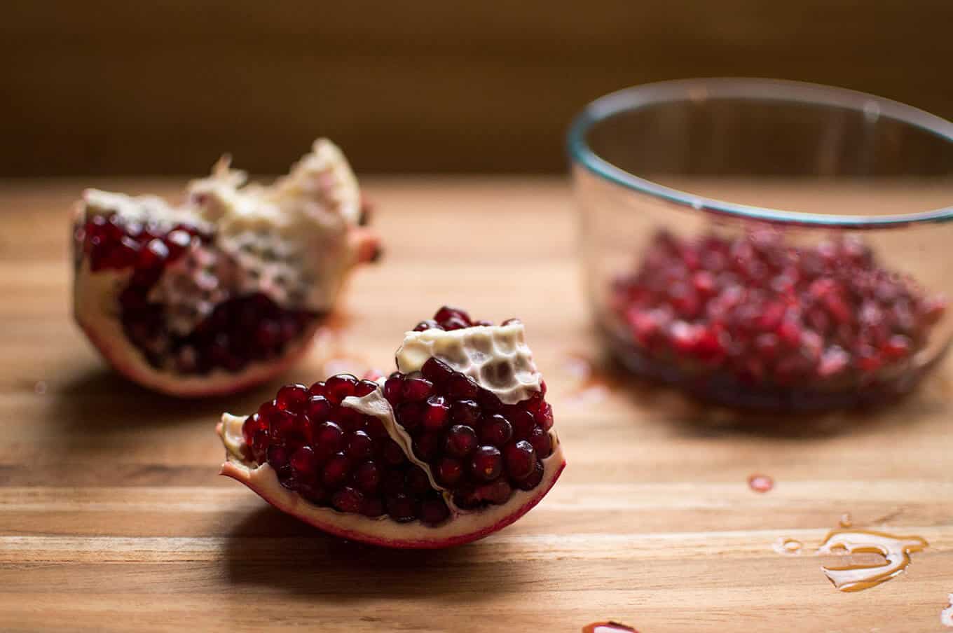 Cut open pomegranate on a cutting board.