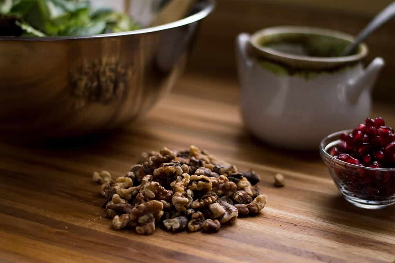 Pecans on a cutting board with bowls in the background.