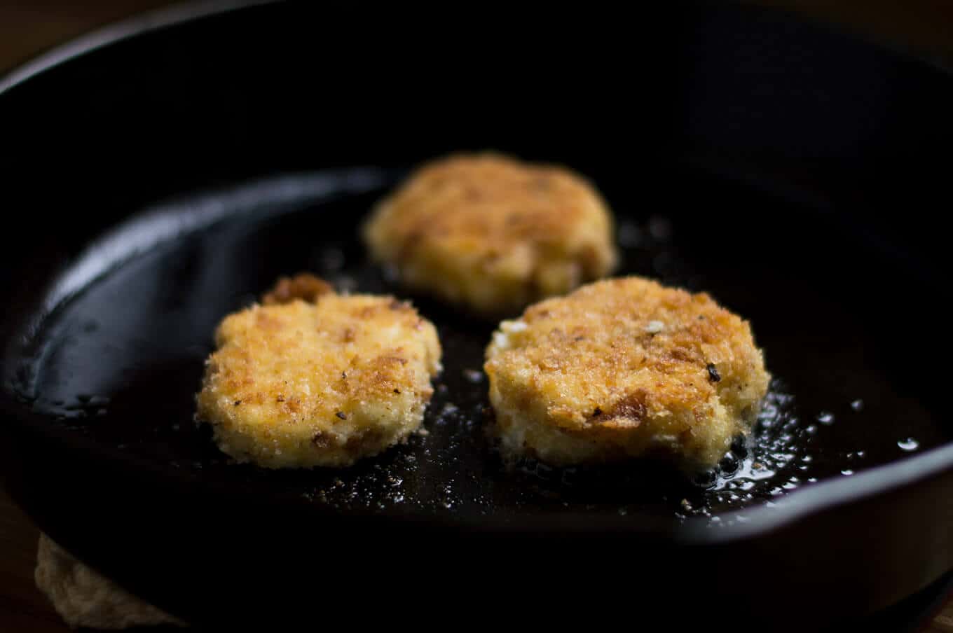 A close up of breaded goat cheese being fried in a pan.