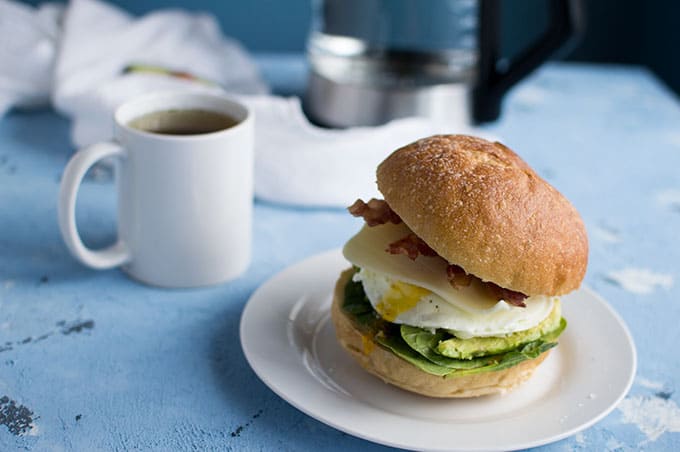 A close up of a plate with an egg sandwich and a cup of tea.