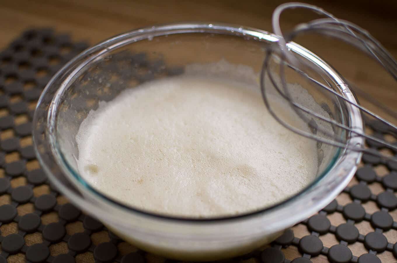 A close up of whipped egg lemon sauce in a glass bowl.