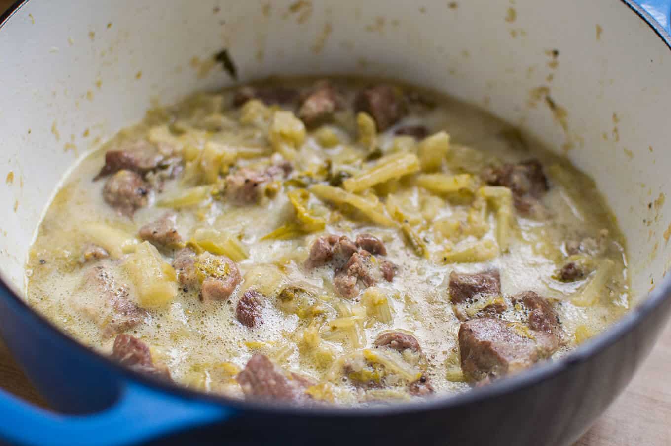 A close up of pork and celery stew in a dutch oven.