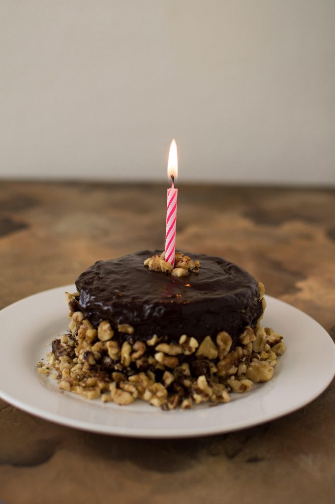 A small cake on a plate with a lit candle.