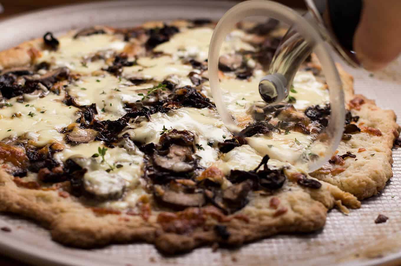 Closeup of a pizza being sliced.