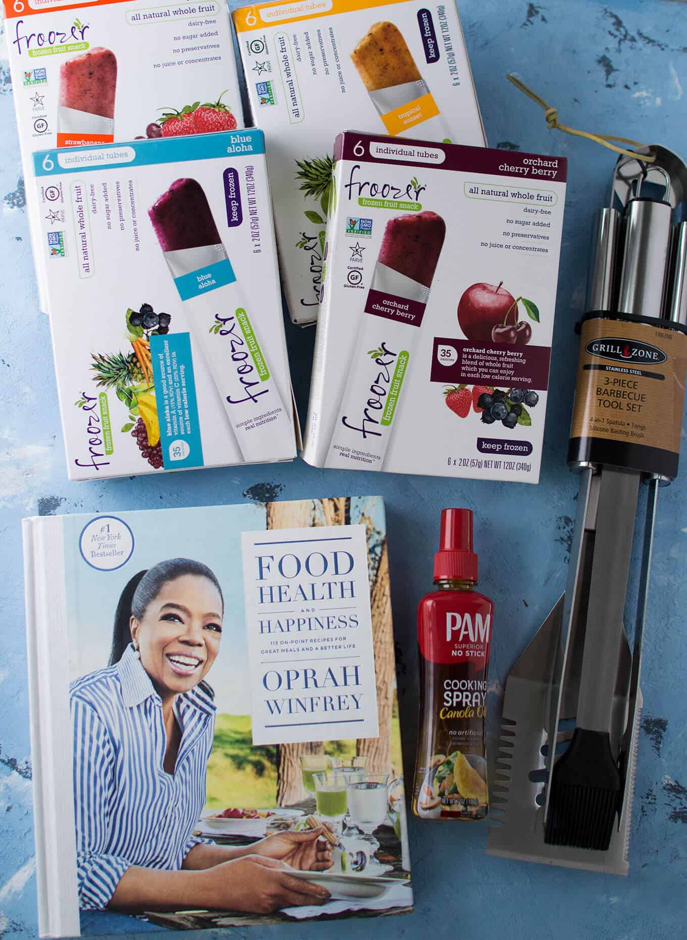 A cookbook, girlling utensils, and boxes of popsicles on a table.