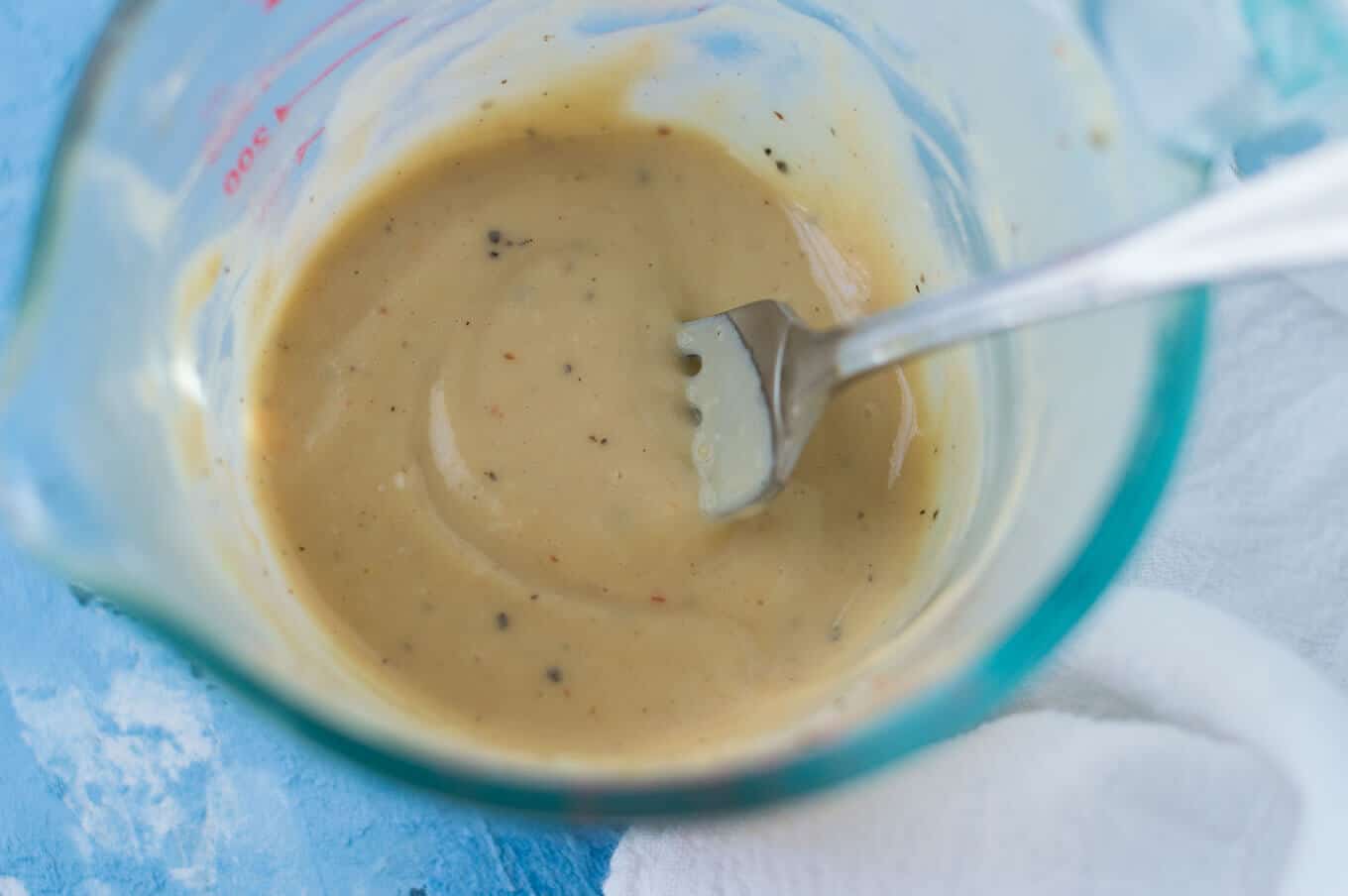 Closeup of homemade dressing in a measuring glass.