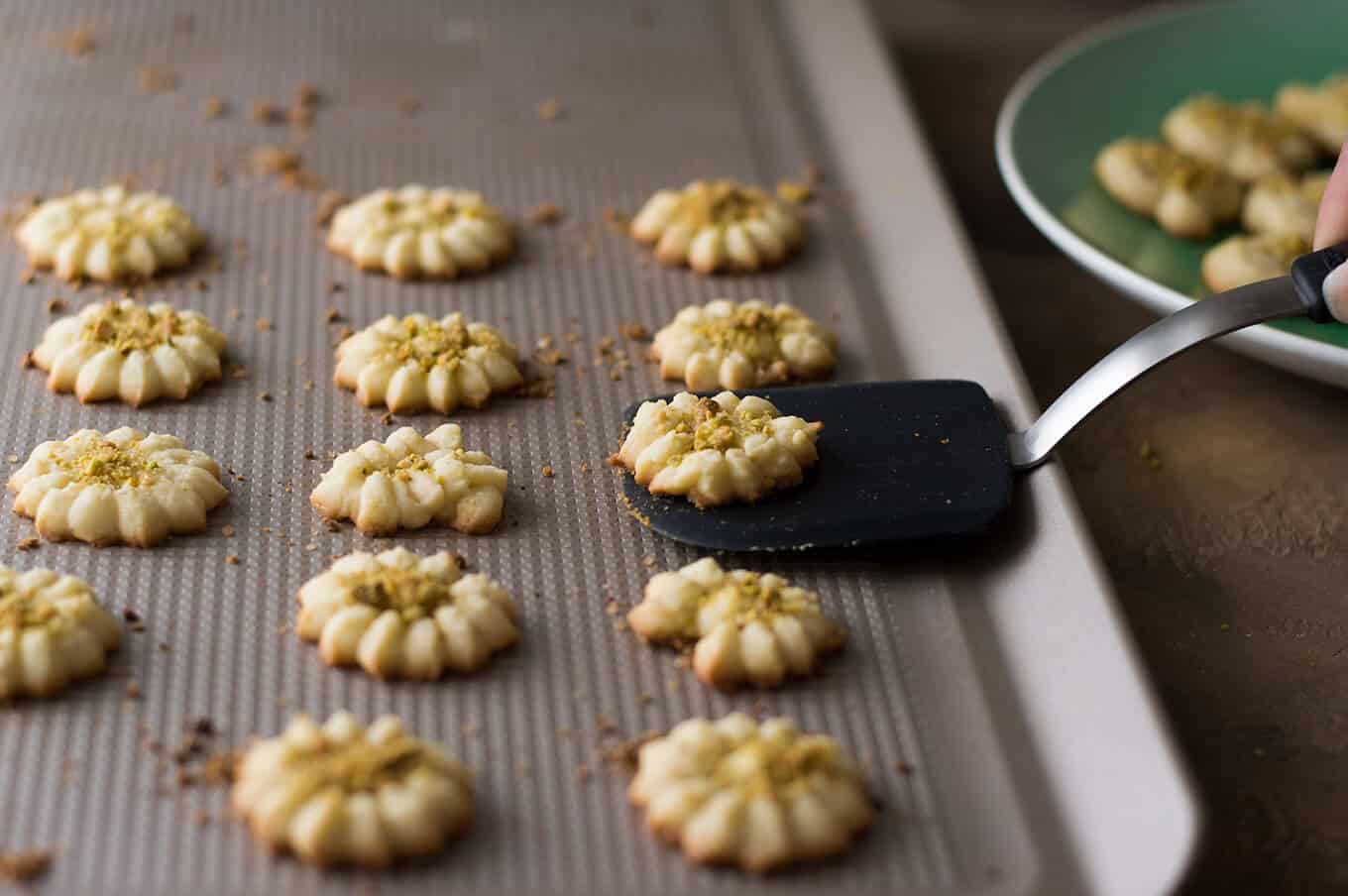 Baked cookies on a baking sheet with a spatula picking up a cookie.