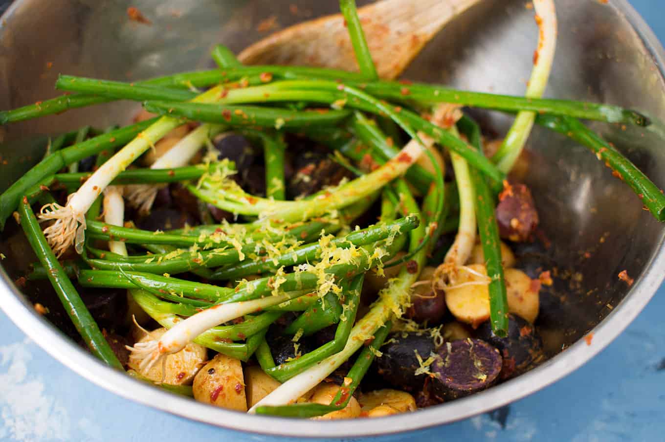 Harissa-seasoned scallions and potatoes in a large bowl.