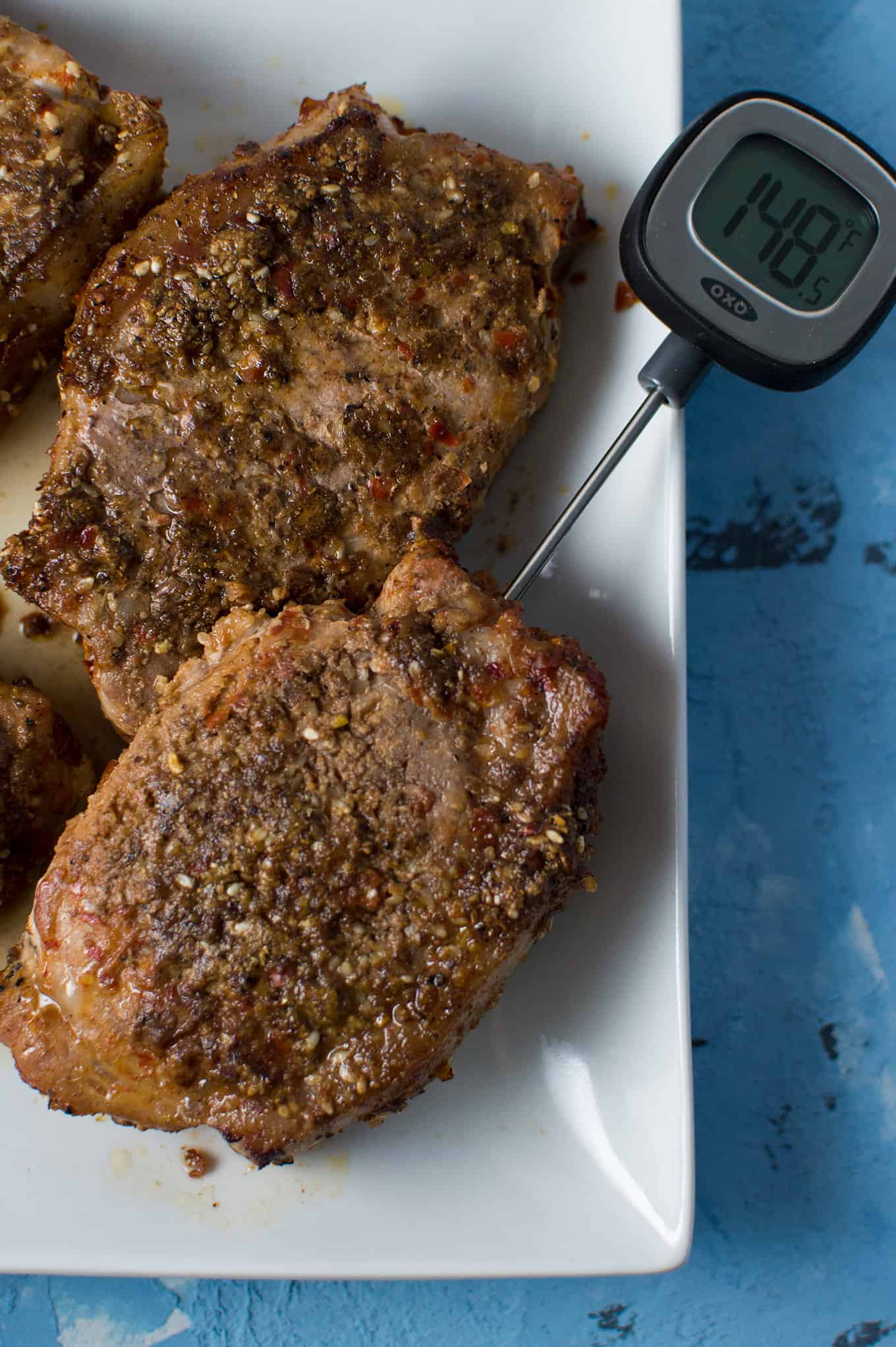 An instant read thermometer inserted into a cooked pork chop.