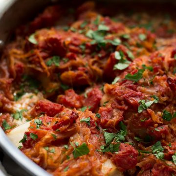 Close up of psari plaki in a stainless steel pan.