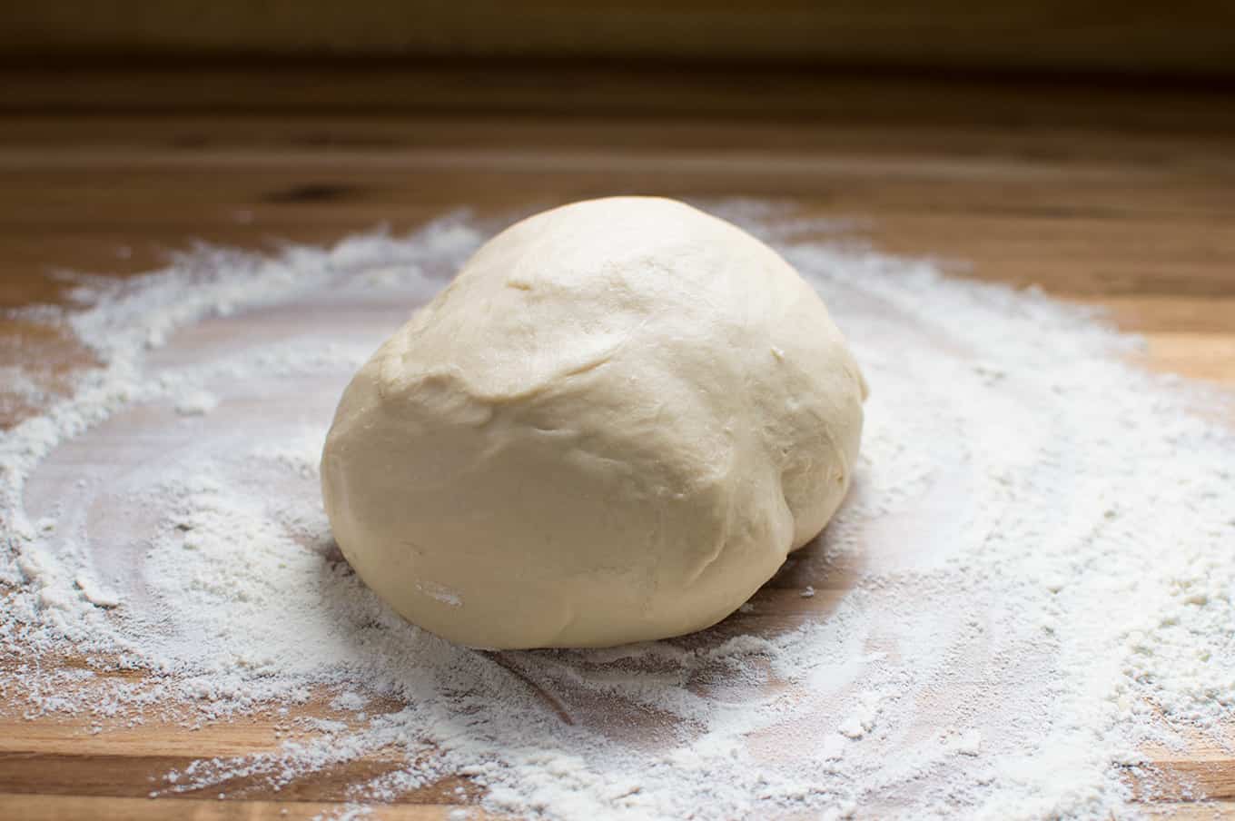 A ball of dough on a floured cutting board.