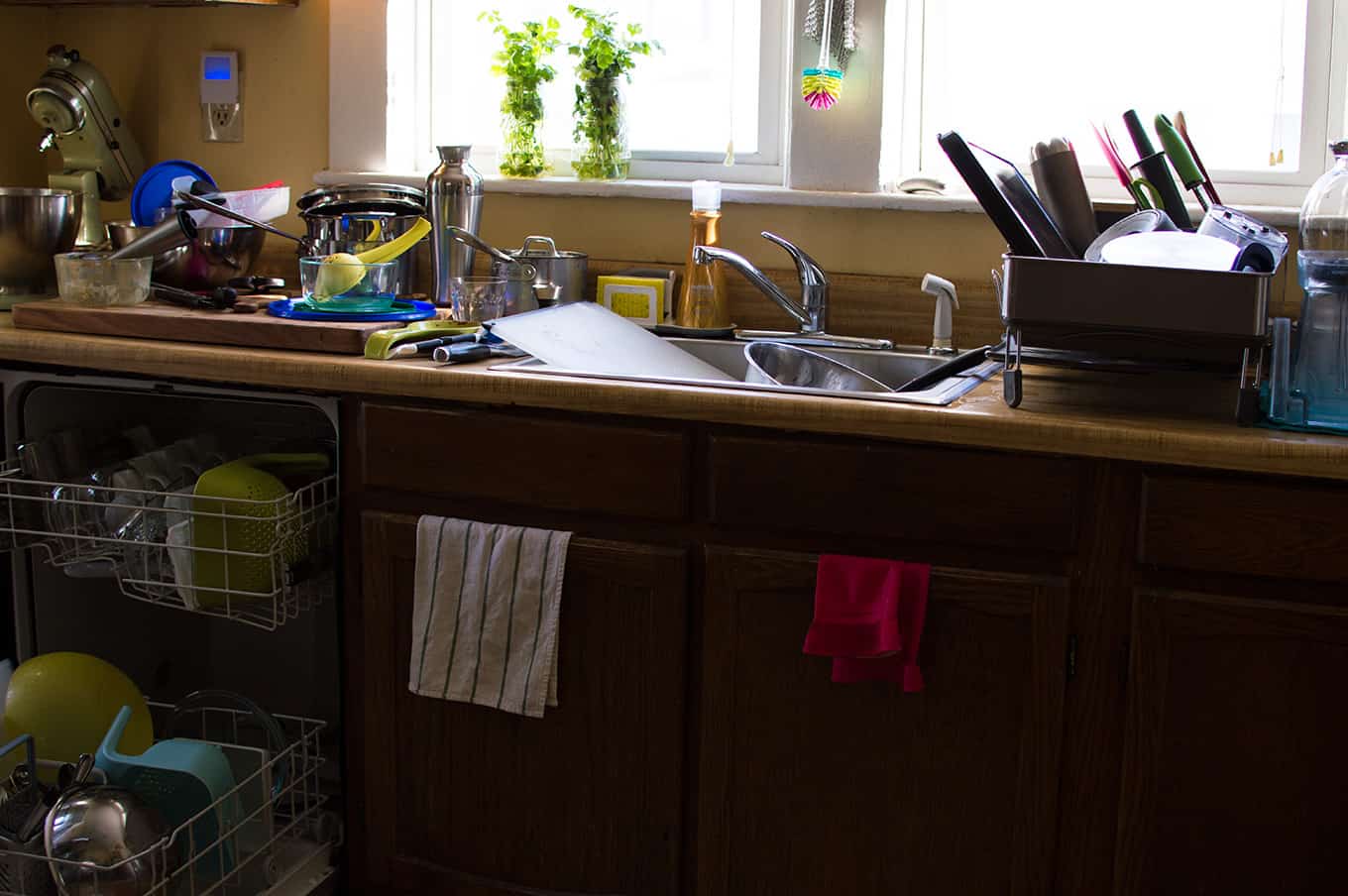 A messy kitchen with dirty dishes on the counter and sink.