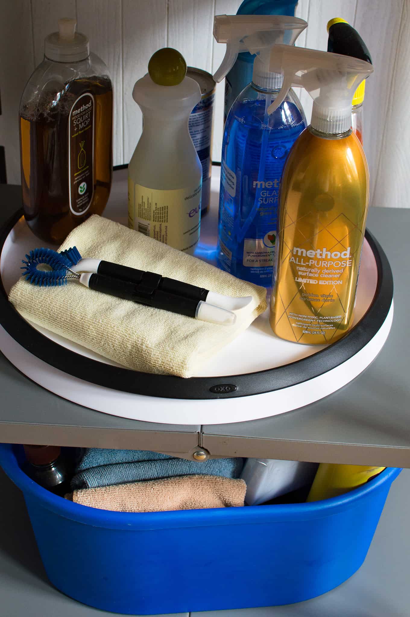 Assorted cleaning supplies and towel on a rotating tray.