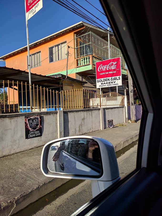 A car parked on the side of a road in front of a store.