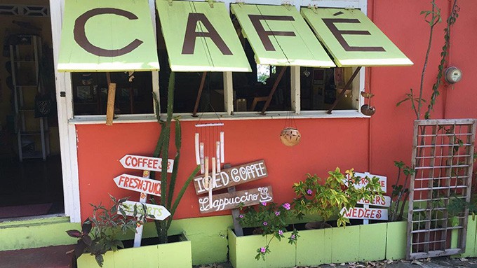 Restaurant front with signs and planted flowers.