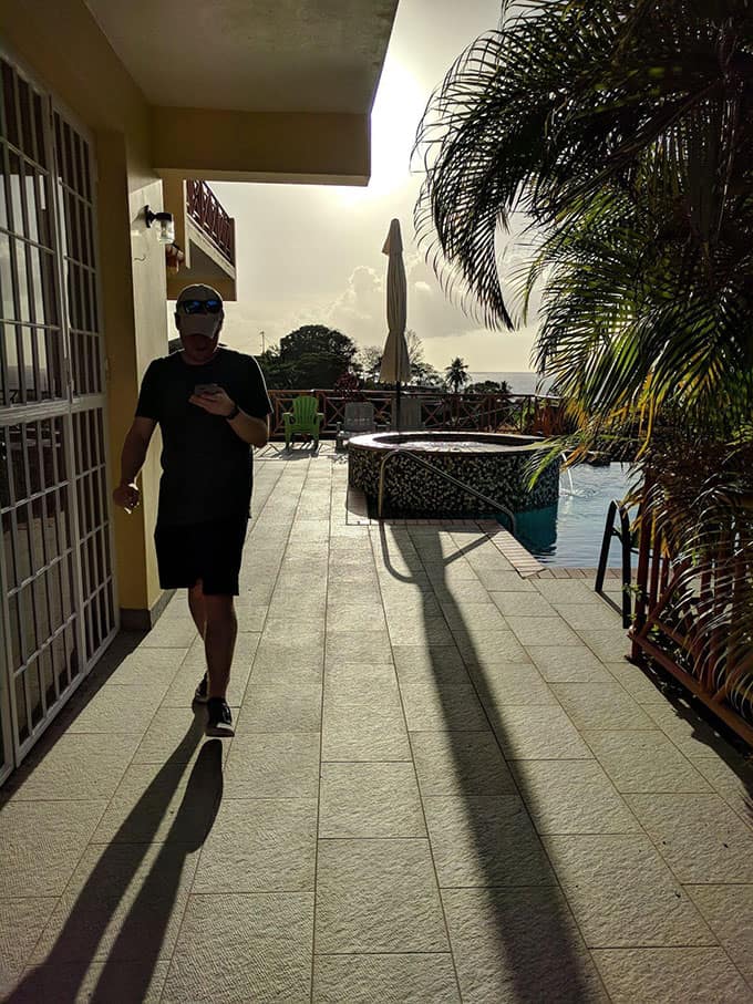 A man walking through a pool area outside of a home.