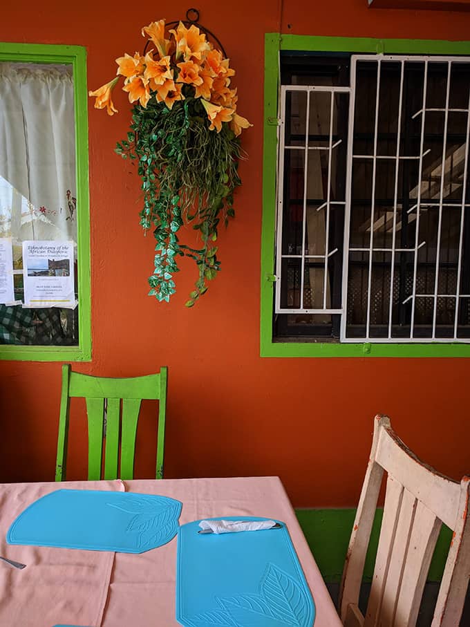 An outdoor dining table in front of a bright orange wall.