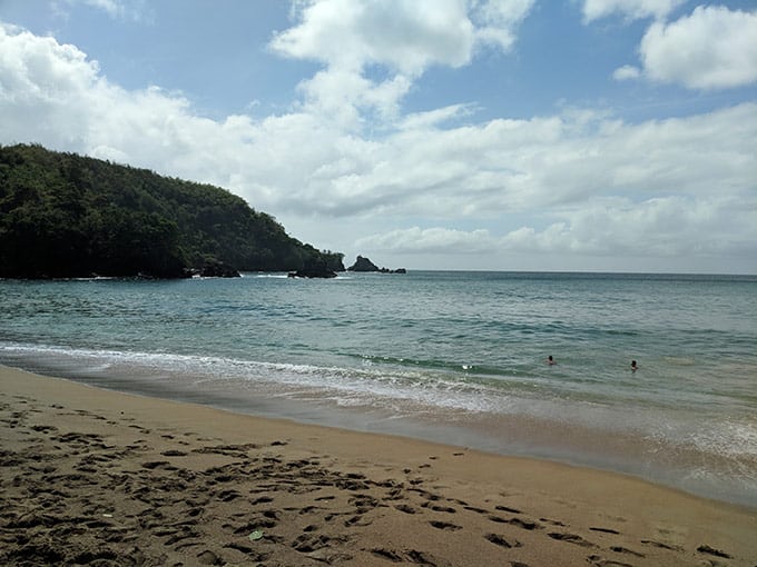 A beach with people swimming in the ocean.