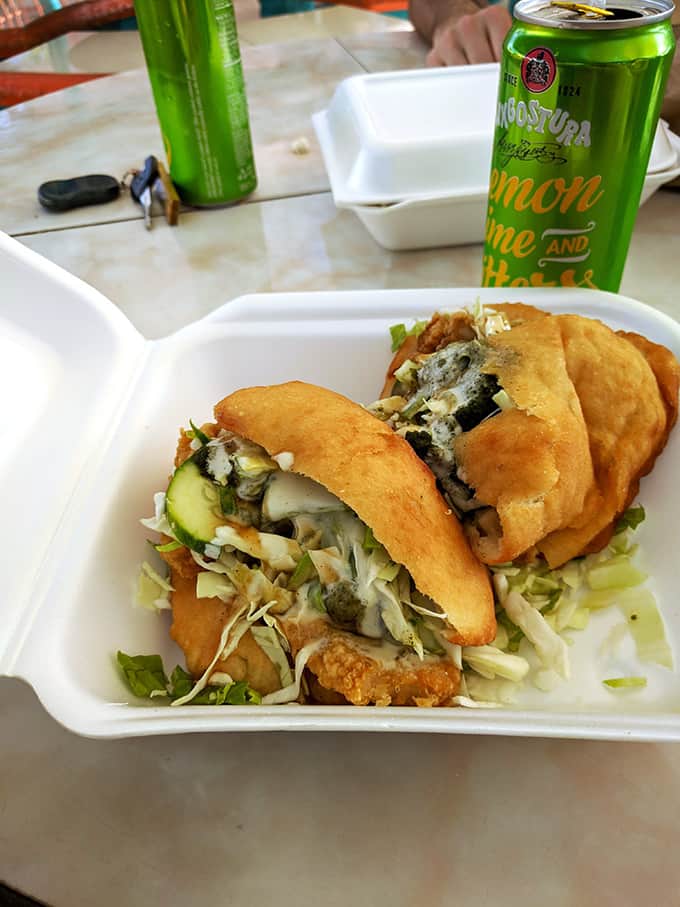 Close up of a bake and shark sandwich in an open takeout container.