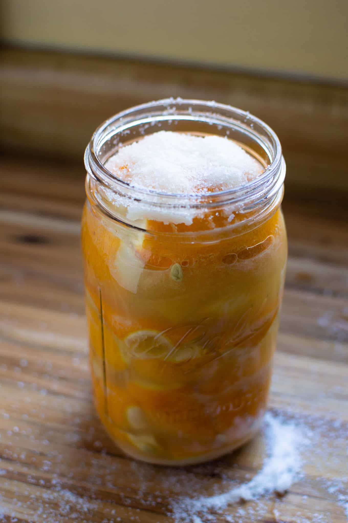 A mason jar full of lemons and juice, topped with salt.