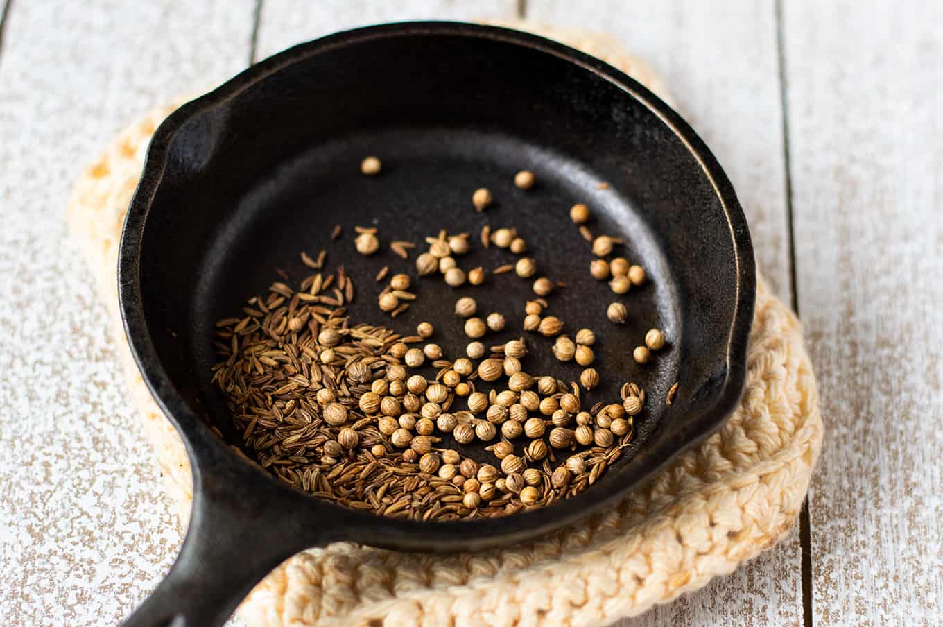 A close up of a whole spices in a small cast iron pan.