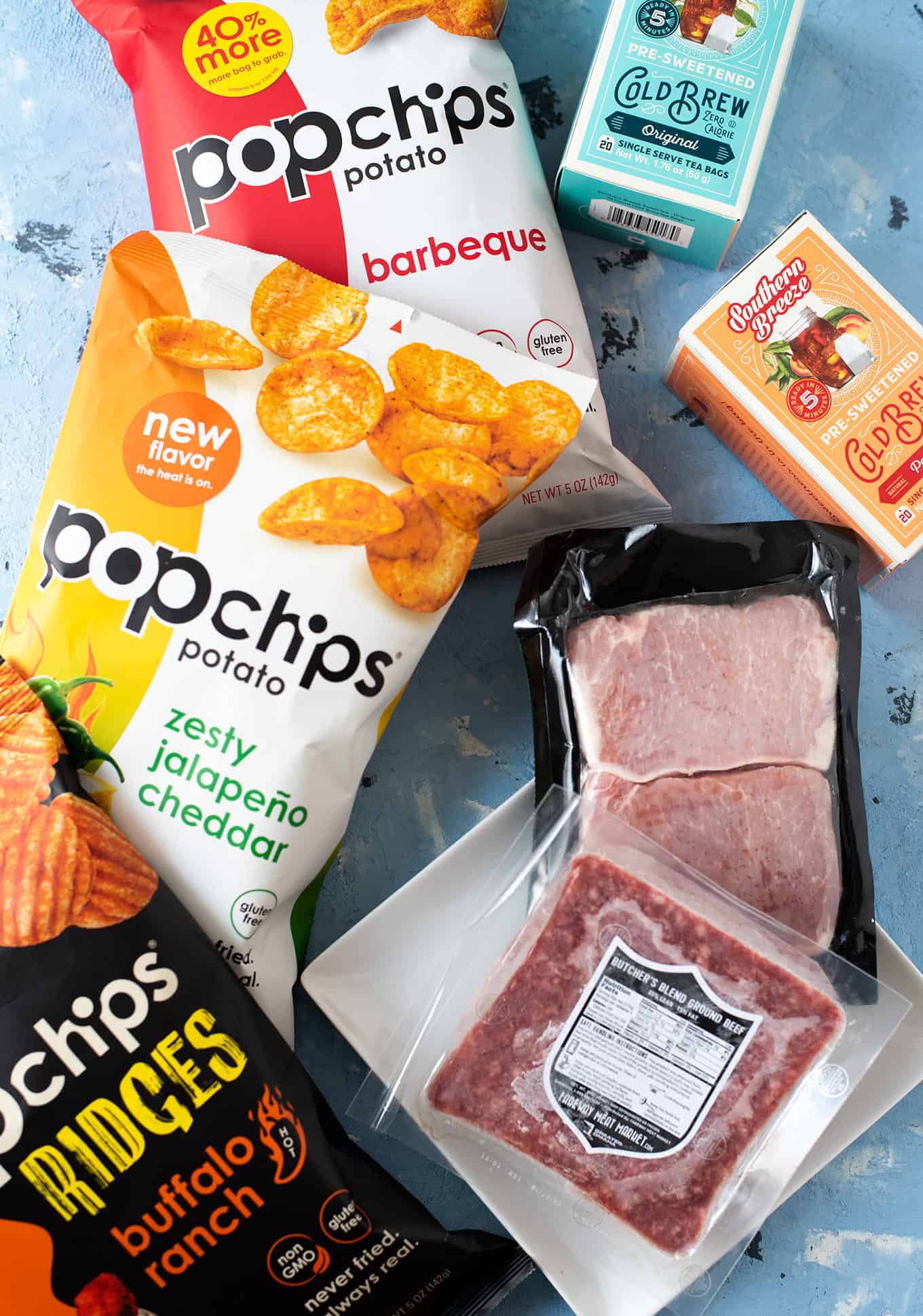 Assorted bags of Popchips, packaged cold brew teas, and packaged pork.