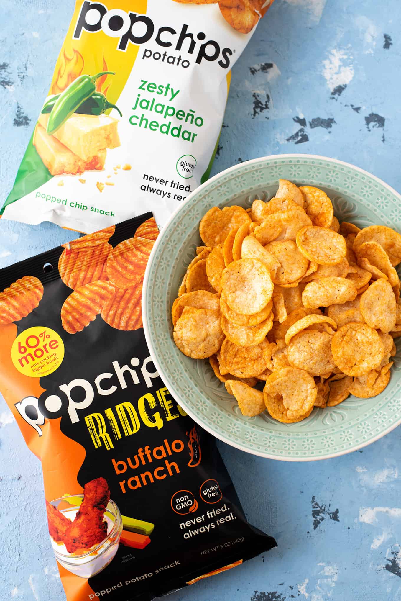 Top-down view of chips in a bowl and two bags of Popchips on a table.