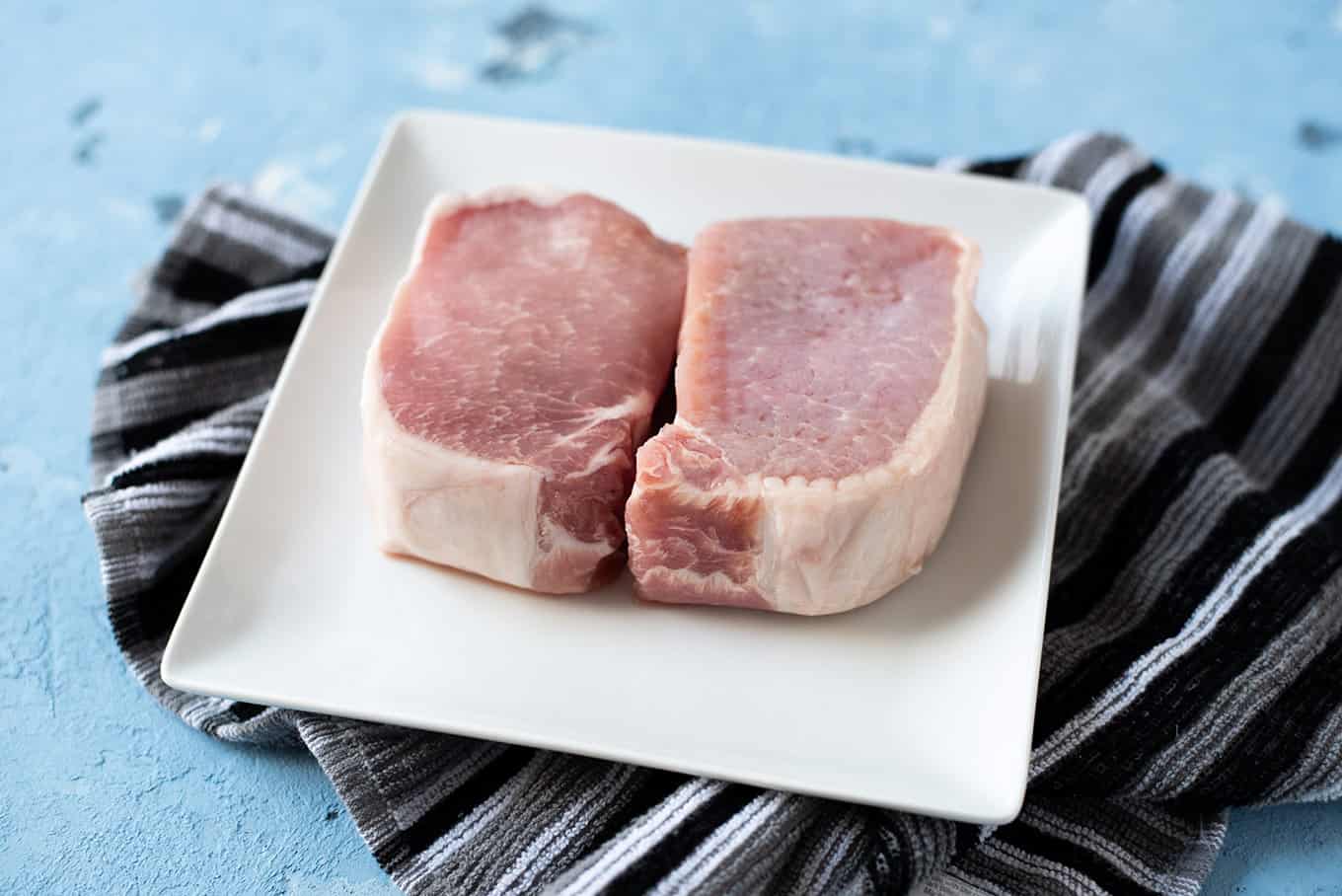 Raw pork chops on a plate.