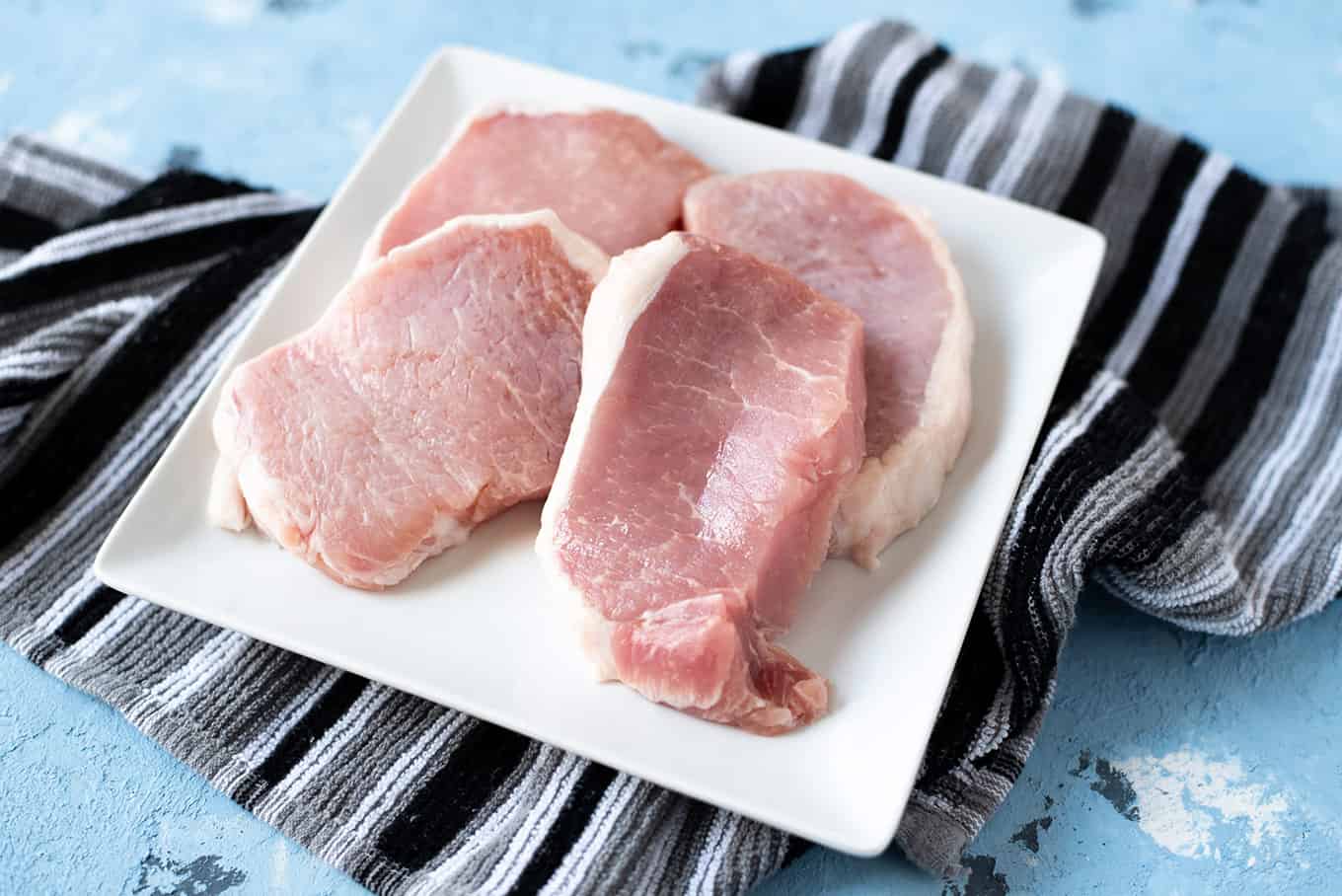 Sliced raw pork chops on a plate.