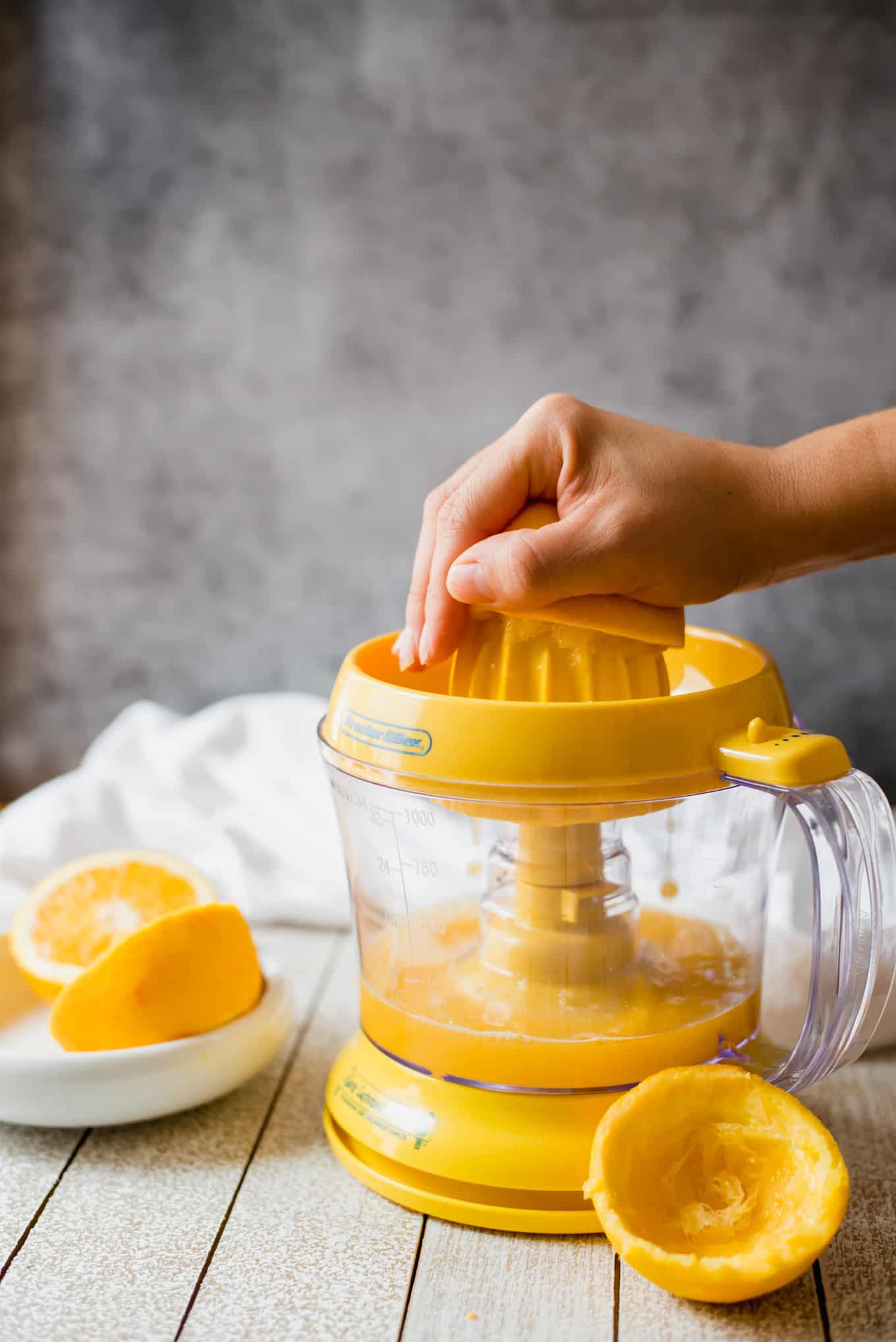 A hand pressing an orange against an electric juicer.