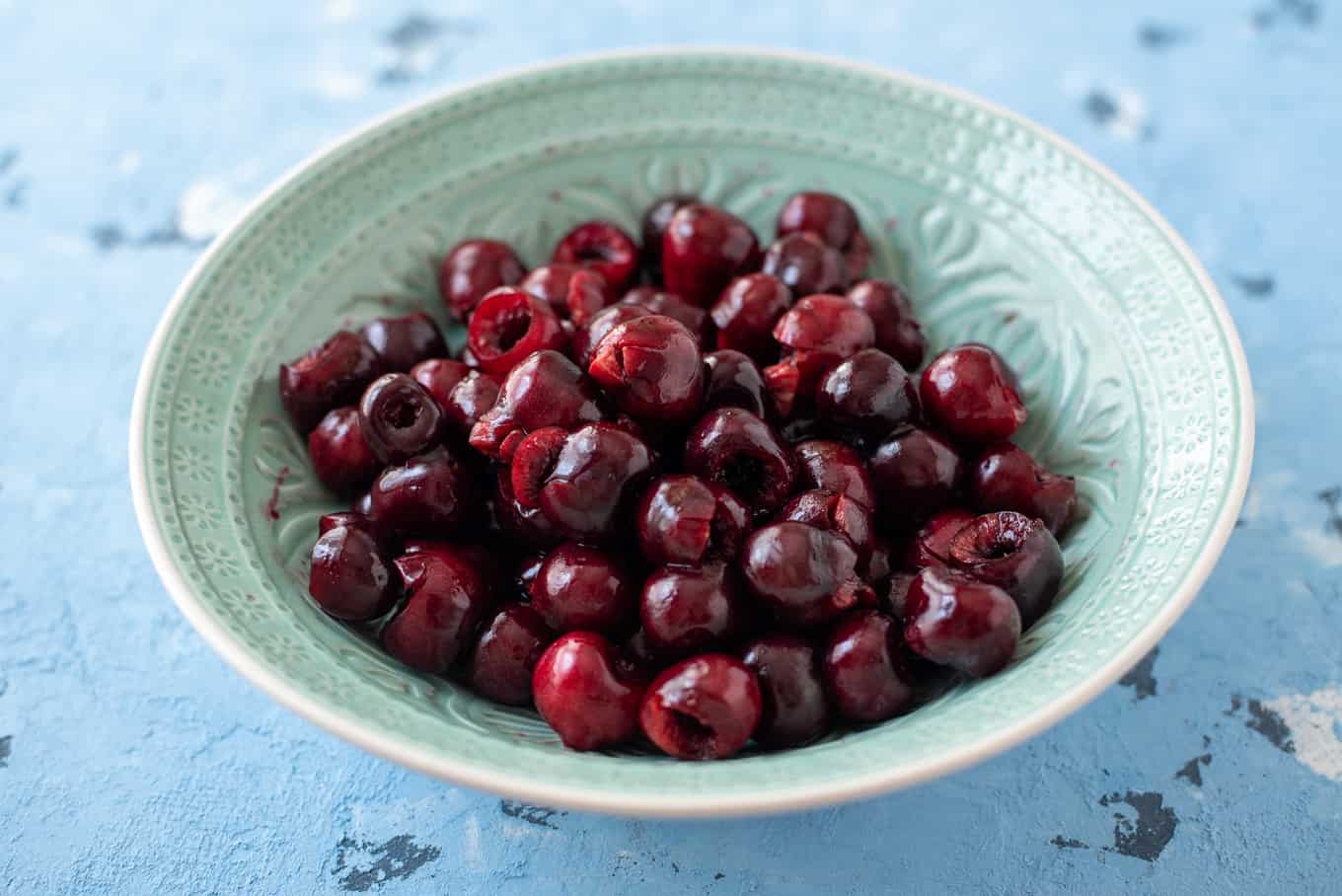 A bowl of pitted cherries on a table.
