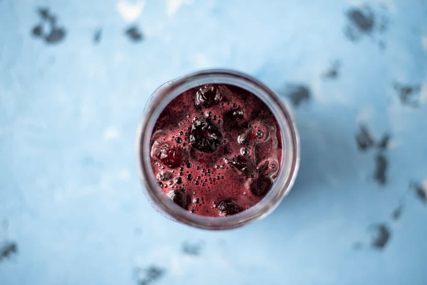 A close-up of cherry preserves in a glass jar.