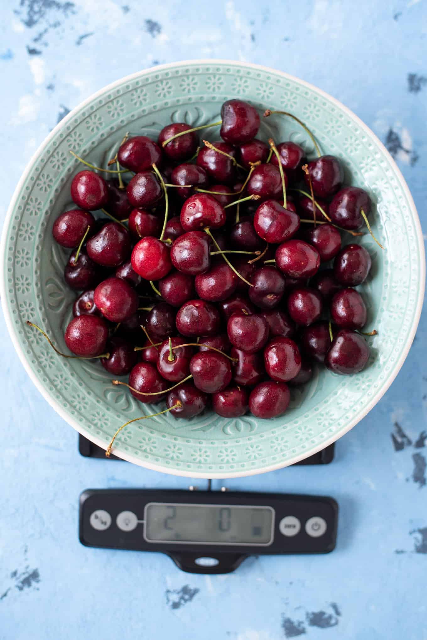 Cherries in a bowl on a food scale. 