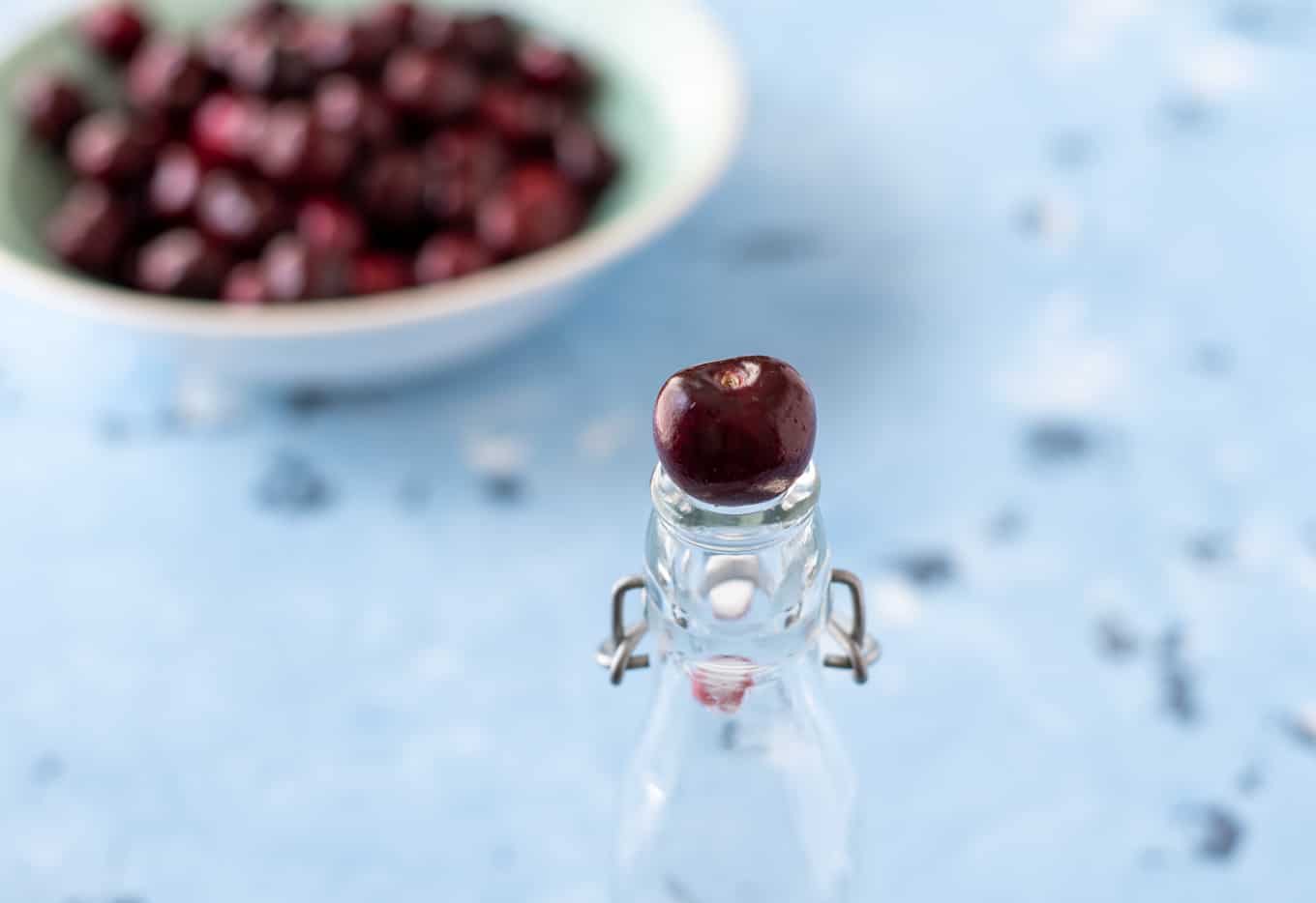 A cherry resting on a bottle top.