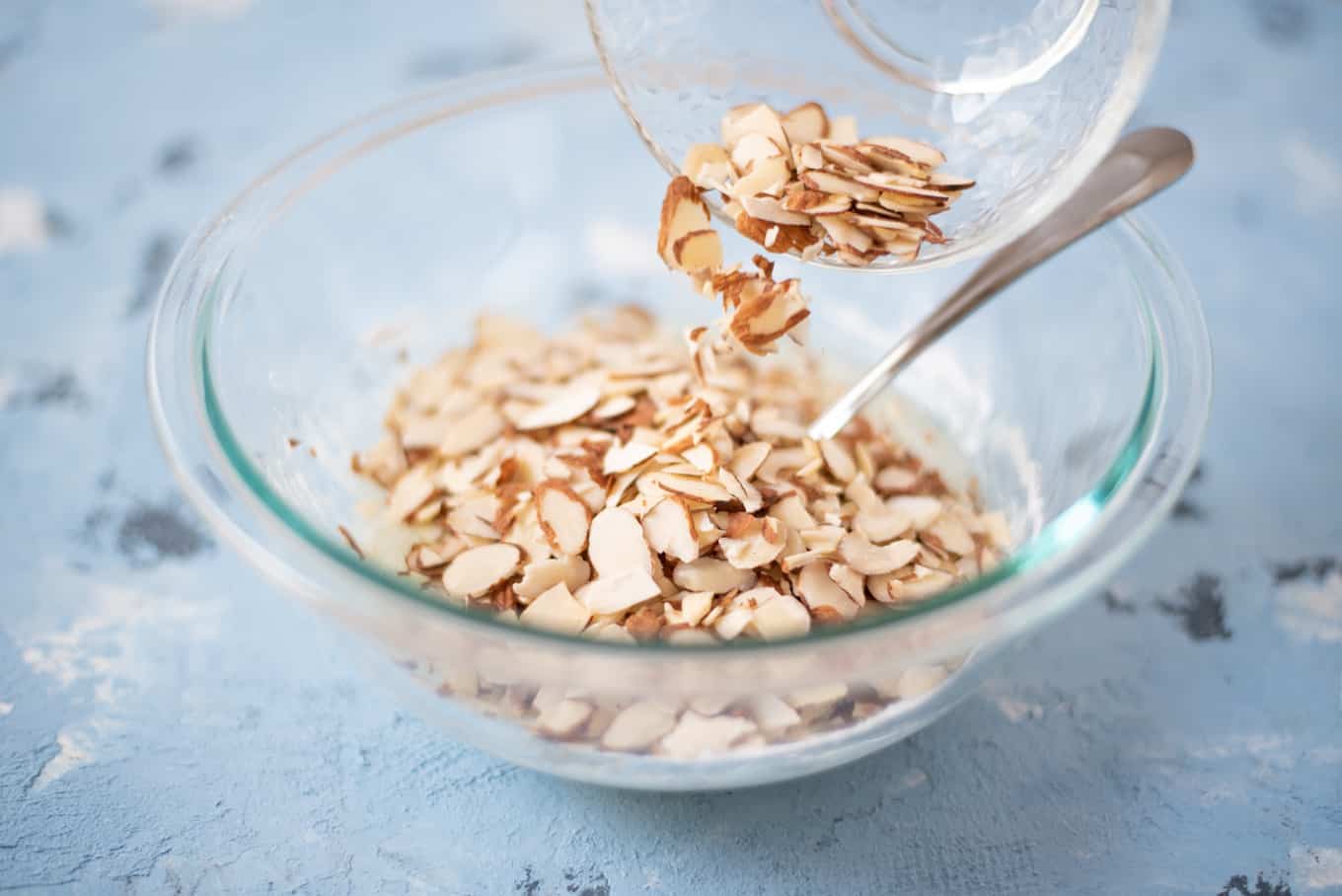 Sliced almonds being poured into a bowl.