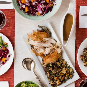 A table topped with various plates of food for Thanksgiving.