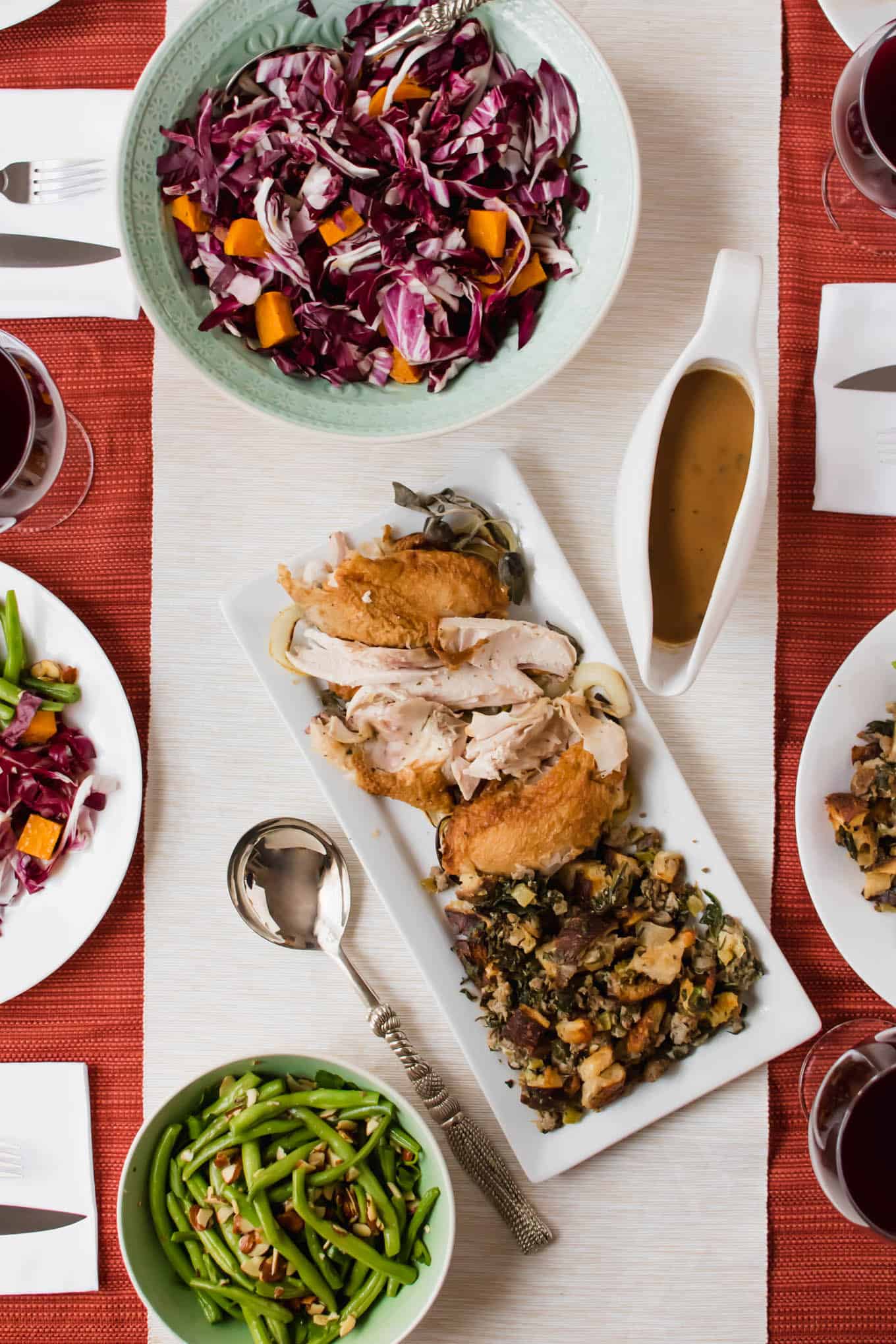 A table topped with various plates of food for Thanksgiving.