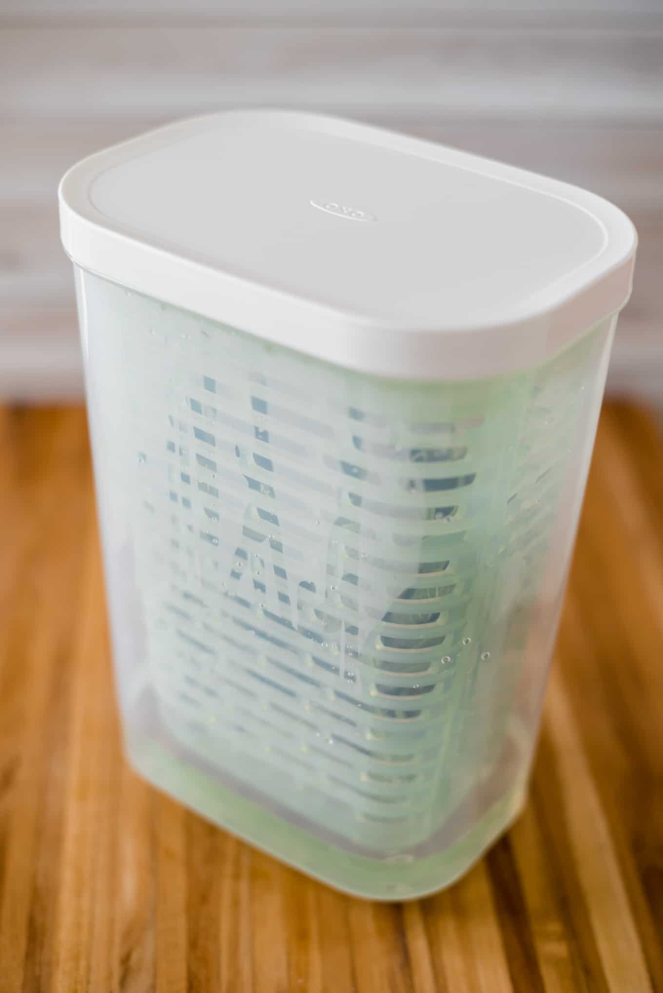 A plastic herb container with fresh sage inside.