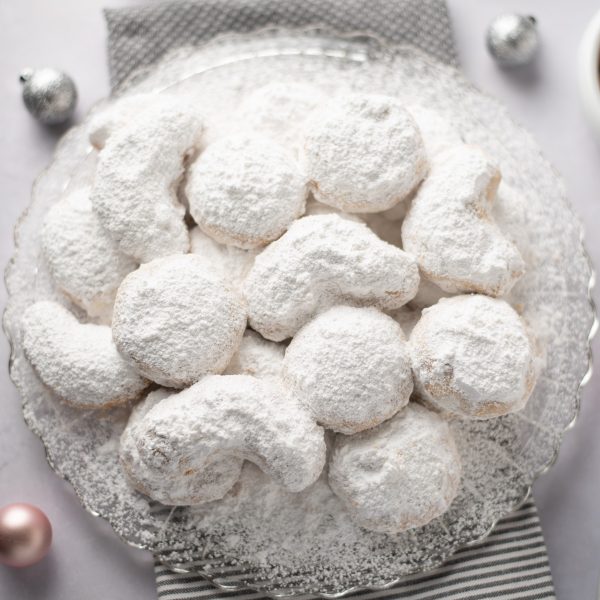 Featured image: Close up of powdered sugar cookies on a platter.