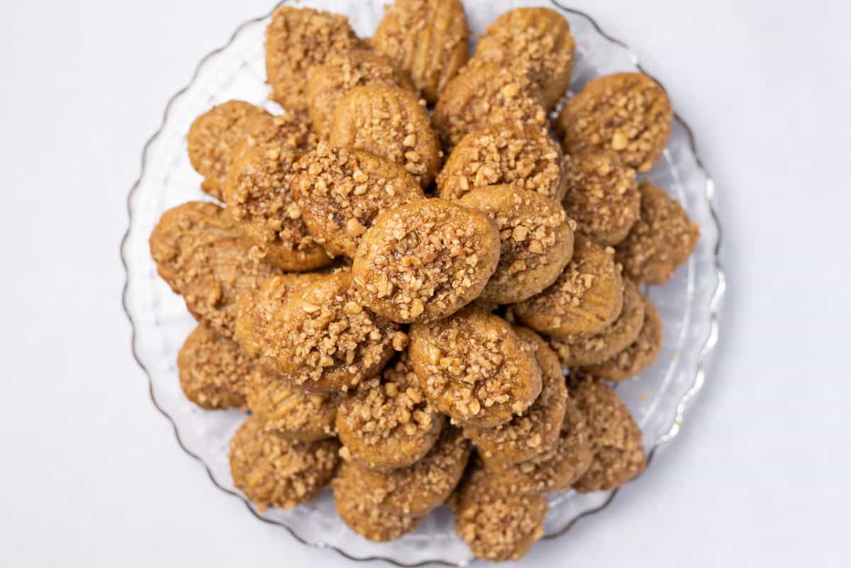 Close up of Greek honey cookies stacked on a glass platter.