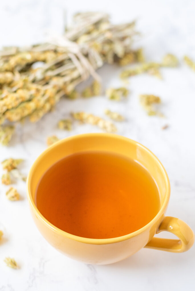 A cup of tea on a tabletop with scattered tea leaves.