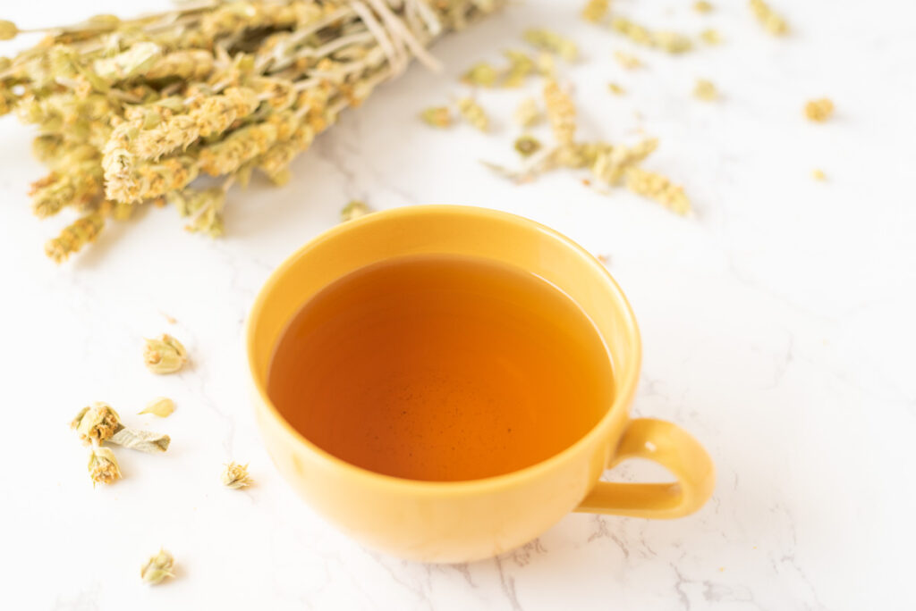 A cup of tea on a tabletop with scattered tea leaves.