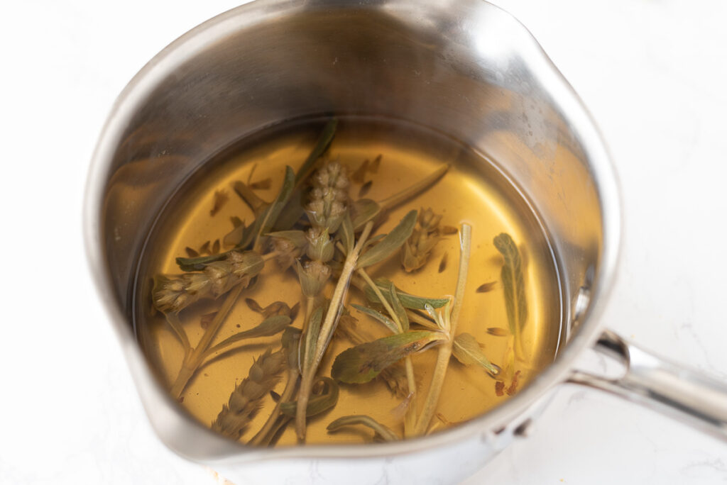 A pot of steeped tea with stems and leaves.