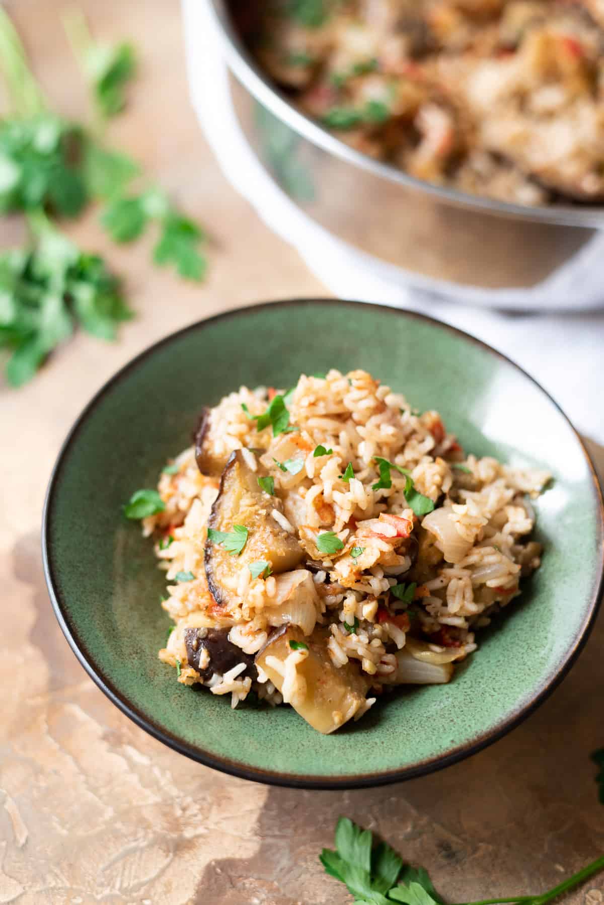 Close up of eggplant and rice in a bowl with a pan of casserole in the background.