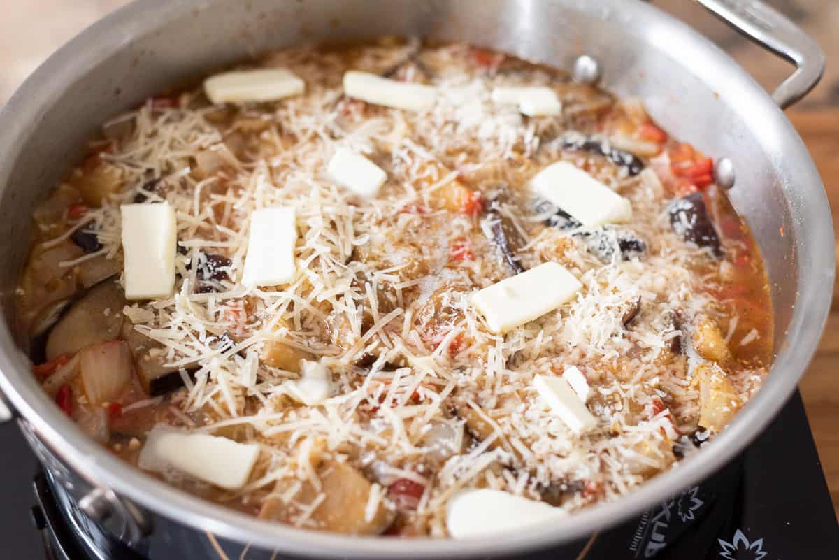 Eggplant and rice casserole in a pan on an induction cooktop.